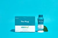 A box of The Plug Drink beside a bottle on teal
