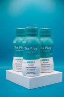 Three bottles of The Plug Drink on a teal studio set