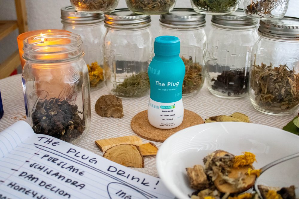 Jars of dried Korean herbs beside a bottle of The Plug Drink
